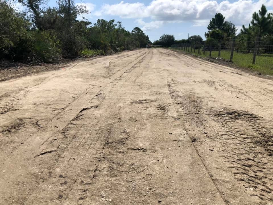 Wide graded dirt road cut through brush and pines on a Harrack job
